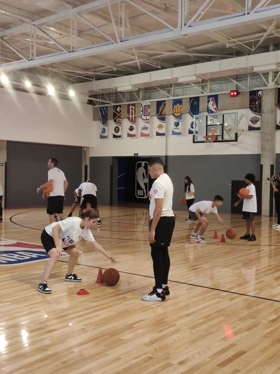 Atletas do Instituto Gomes Basquete praticando drible em quadra durante evento dos 75 anos da NBA